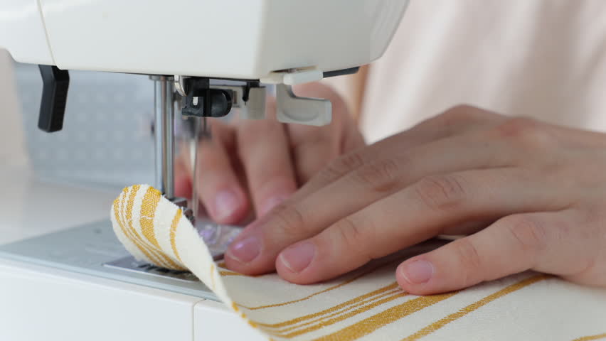 woman sews clothes on sewing machine. manufacture of dresses, shirts. hobbies professional sewing skills. factory for production of fashionable clothing collections. steel needle.