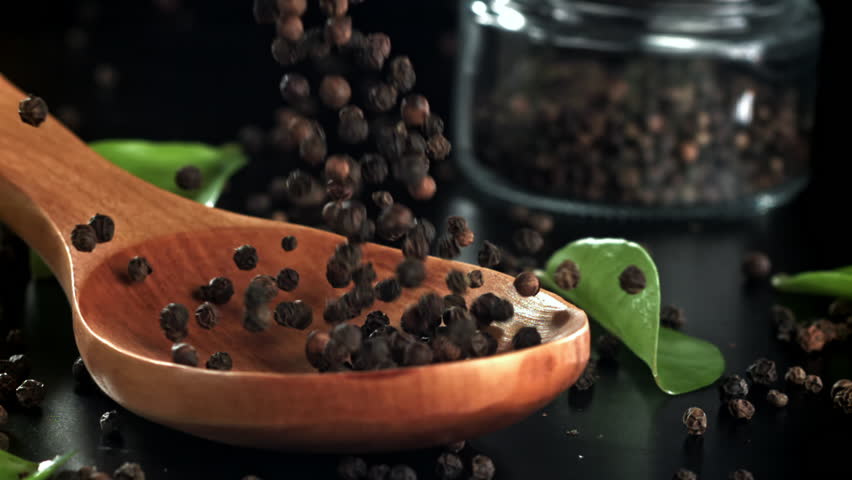 Black pepper falls on a wooden spoon. Filmed on a high-speed camera at 1000 fps. High quality FullHD footage
