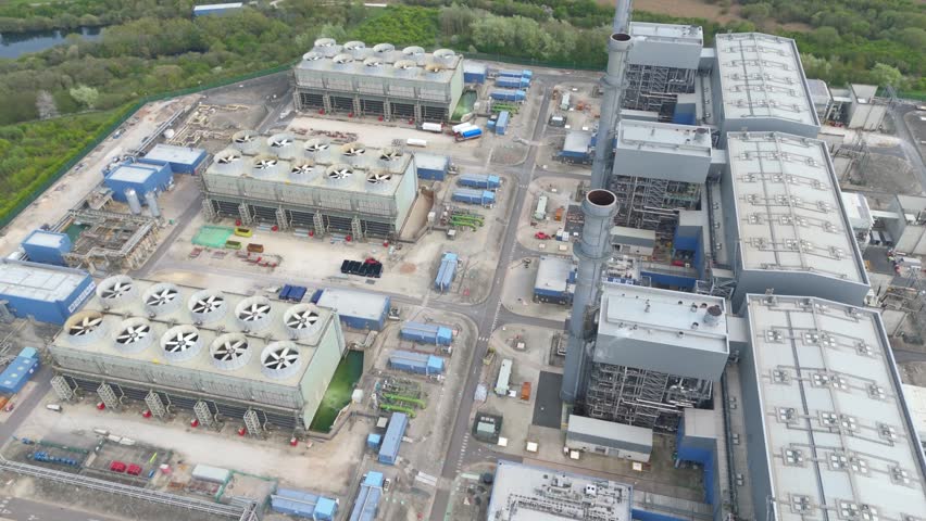 Drone footage of a vast industrial facility surrounded by green fields and a winding river.