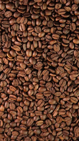 Vertical video roasted coffee beans rotating as background close-up wide angle. Concept for coffee shop with brown coffee beans rotating as background for advertising, promo, vending machine