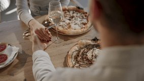 Couple enjoying a cozy dinner, holding hands across the table, with wine and gourmet pizza creating a romantic atmosphere - Powered by Shutterstock - Get 15% off with code: PIKWIZARD15