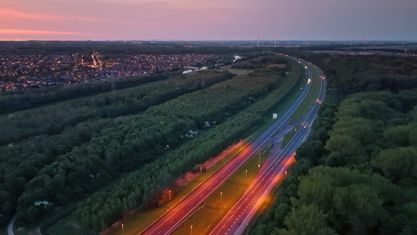 Calm drive through Dutch fields. Twilight illuminates a peaceful road winding through lush green fields in the Netherlands, surrounded by a small town.