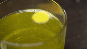 A hissing cold pill with vitamin C and lemon flavor dissolves on the surface in a glass of hot water. Slow motion. Close up. - Powered by Shutterstock - Get 15% off with code: PIKWIZARD15