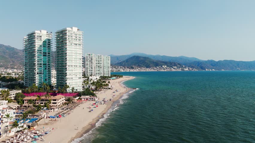 Aerial shot of Playa de Oro with huge buildings on the coastline and the city in the background. Puerto Vallarta, Mexico