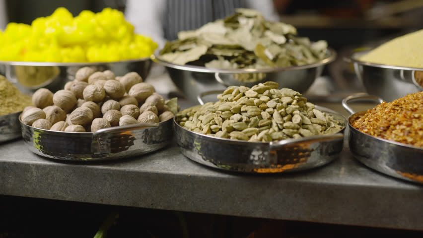 Close-up view of various spices and herbs displayed in a bustling market setting, highlighting culinary diversity.