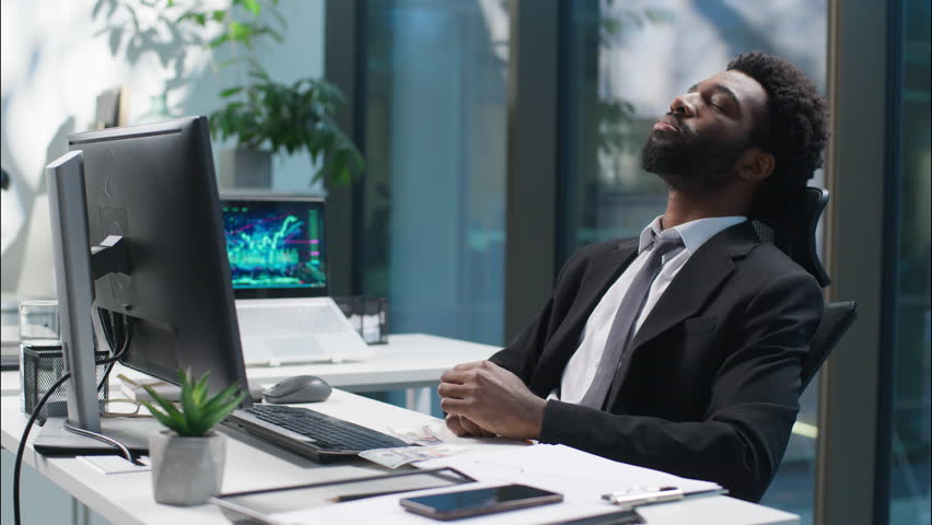 Tired African American man working web online with computer businessman male bored guy business depressed unhappy sad manager employer entrepreneur in office exhausted worker fatigue overwork indoor