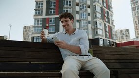 Caucasian young man on bench using mobile phone smartphone app happy male holding cup of coffee drink at city relaxed guy smiling student break weekend businessman business outdoors gadget online - Powered by Shutterstock - Get 15% off with code: PIKWIZARD15