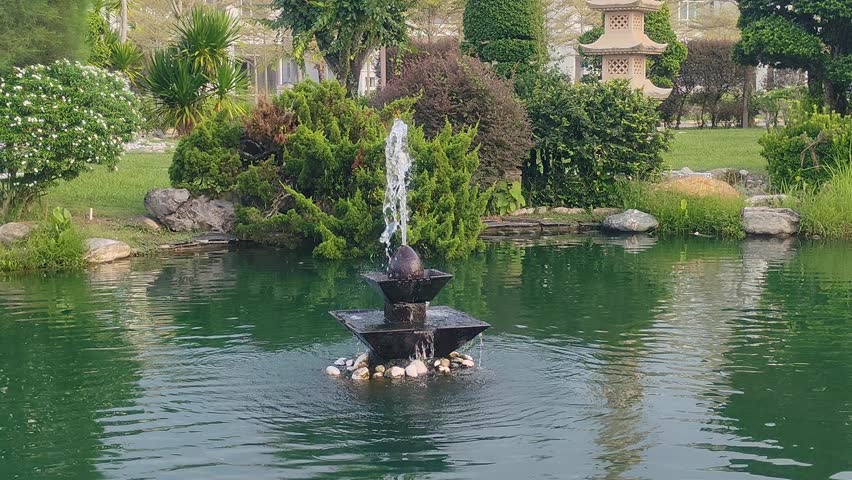Tranquil Fountain in a Lush Garden Pond Surrounded by Greenery