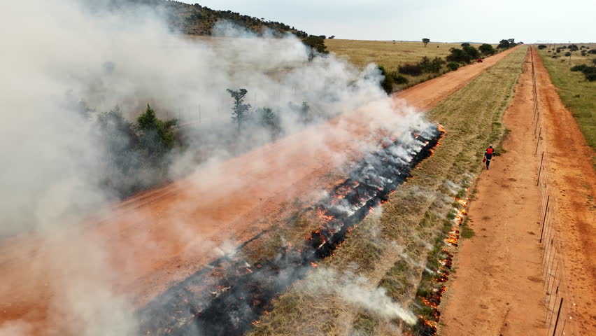 Aerial flyover tracks firefighter creating fire line in wildfire protection zone
