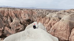 Aerial reveal zoom out view two travelers couple sit in red valley in Cappadocia, central Anatolia, Turkey. Hiking trekking outdoors in Turkey concept having fun couple in love outdoors - Powered by Shutterstock - Get 15% off with code: PIKWIZARD15