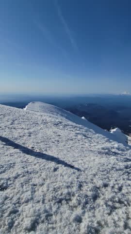 4K vertical mobile video from Mount Hood summit showing Mount Adams, Mount St. Helens, and Mount Rainier under clear blue sky, with distant climbers in spring conditions