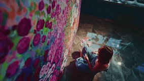 Talented artist sitting on the floor meticulously painting a vibrant and detailed floral mural on a large canvas, adding touches of color to create a stunning piece of art - Powered by Shutterstock - Get 15% off with code: PIKWIZARD15