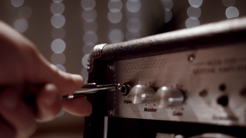 A man turns the volume knob on an electric amp to guitar - Powered by Shutterstock - Get 15% off with code: PIKWIZARD15