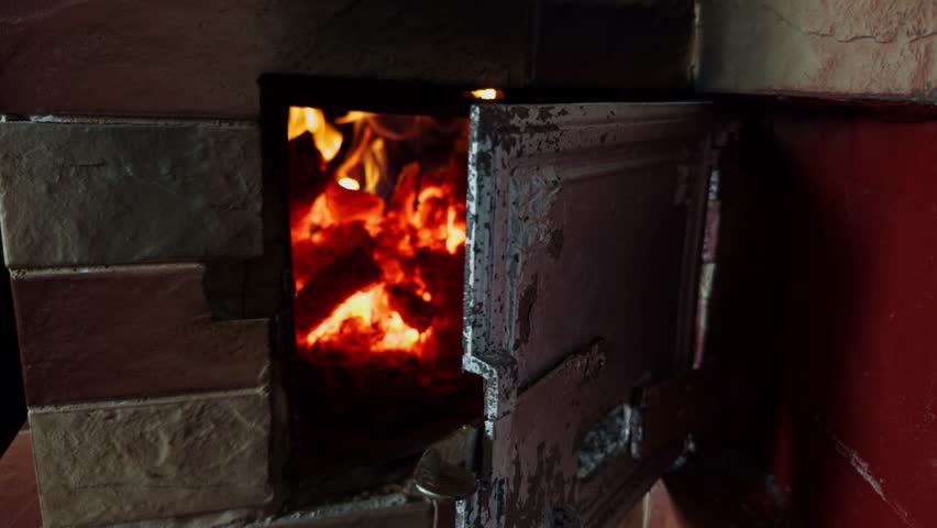 wood stove in old house. Rustic fireplace with burning firewood in cozy brick oven setting. Bonfire in the grill. Logs burning in a wood stove in a living room