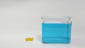 A hand drops pasta into a blue liquid, observing its buoyancy changes in a clear container - Powered by Shutterstock - Get 15% off with code: PIKWIZARD15