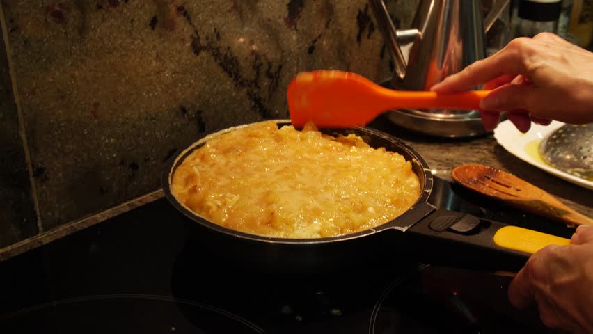 Housewife cooking traditional Spanish omelette at home kitchen. High quality 4k footage.