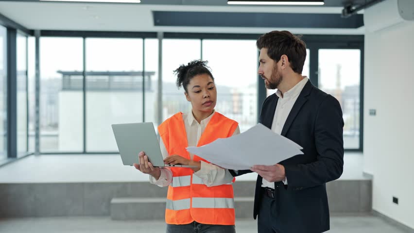 Female professional architect and investor discuss blueprints in modern office. Investor holds documents, and architect uses laptop. Successful teamwork, confidence, and expertise. - Powered by Shutterstock - Get 15% off with code: PIKWIZARD15