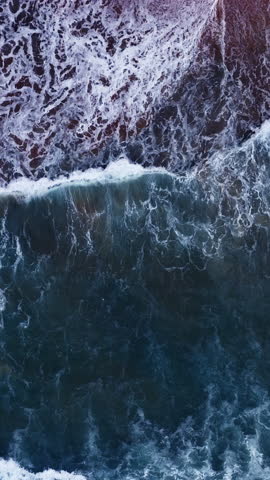 Vertical video of Drone aerial view of waves crashing on beach,Amazing sea water and sand at sunset or sunrise light,Vertical view High quality video ProRes 422,Seashore background