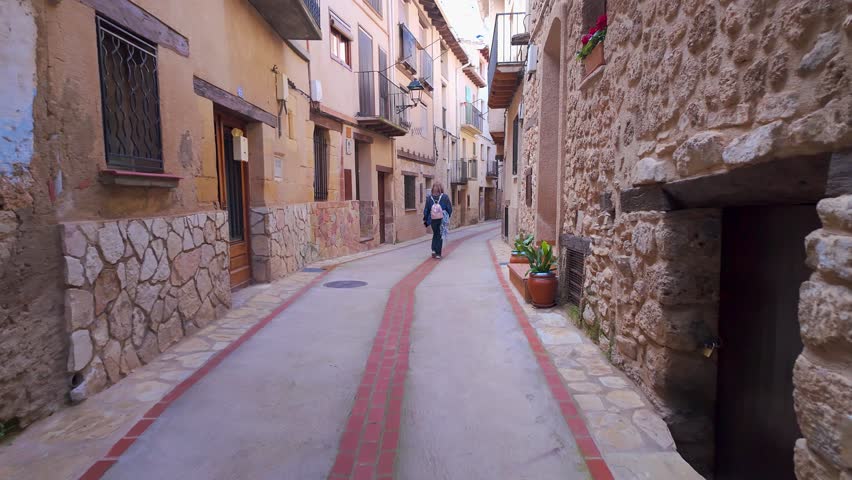 Tourist woman strolling through the streets with stone arches in the medieval village of Beceite, Teruel, Spain.