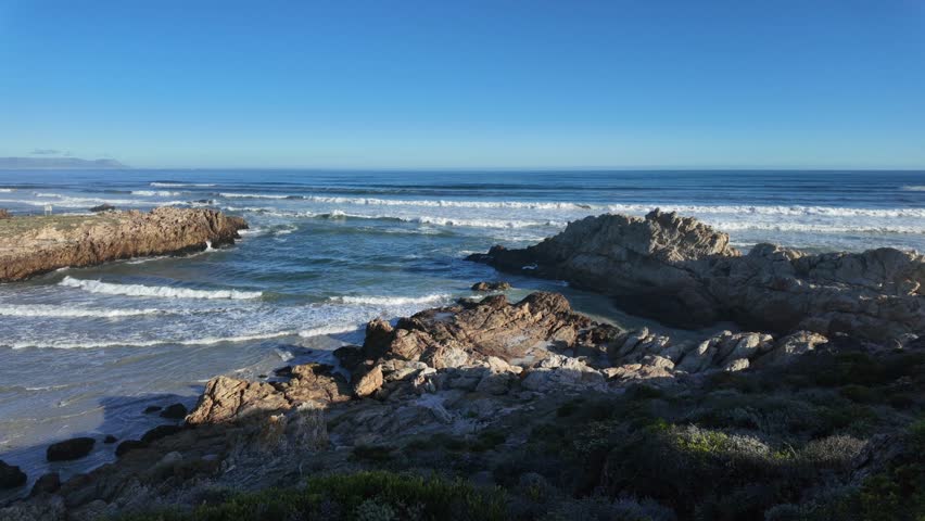 Afternoon view of the stunning Hermanus coastline in South Africa, showcasing dramatic cliffs, turquoise waters, and rugged beauty—perfect for travel, tourism, and nature-themed visuals.