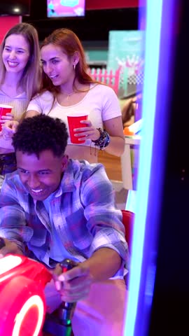 Young adults experiencing vibrant arcade gaming excitement at bowling alley, immersing themselves in colorful simulator challenges and shared entertainment