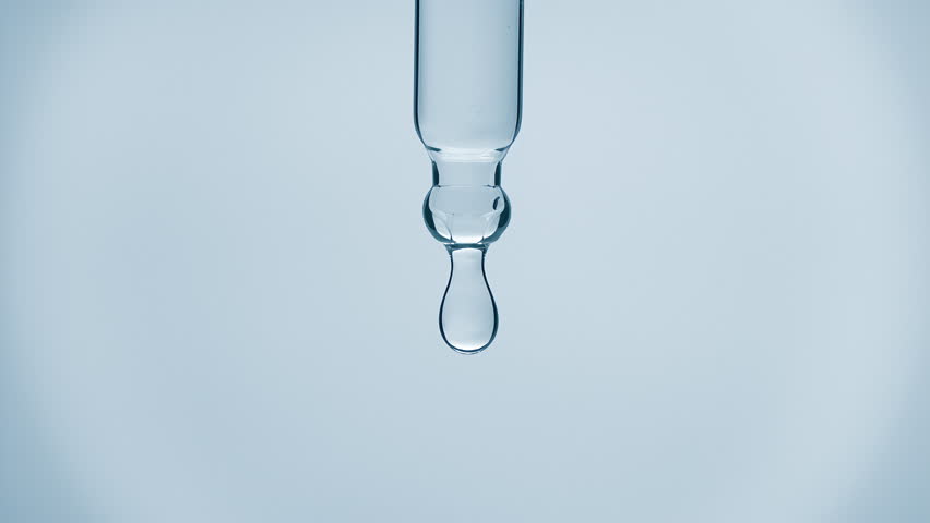 Cosmetics blue liquid dripping from laboratory glass pipette in super slow motion. Macro shot of drop hanging down from chemical dropper. Abstract body care serum ingredients formulating concept