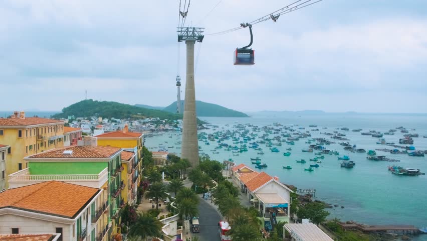 Aerial view of Sunset town and coastal fishermen village with colorful houses, fishing boats, turquoise sea and modern cable car ride on Phu Quoc island, Vietnam. Modern Hon Thom cable car cabin