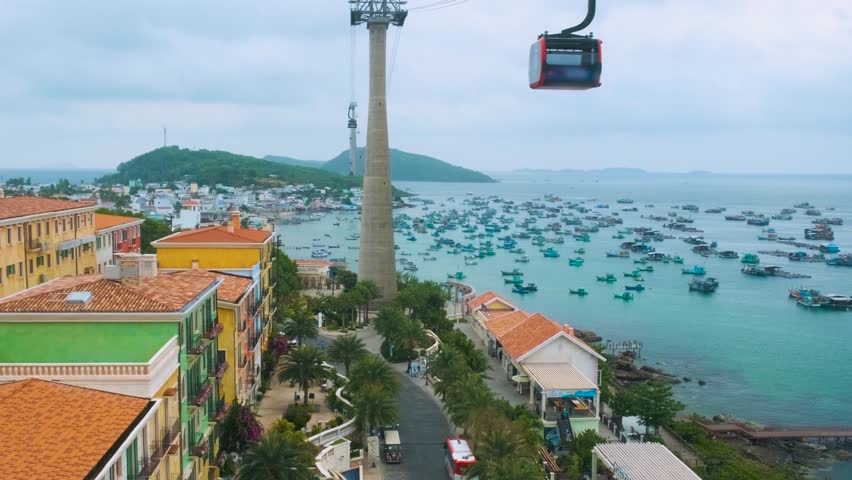 Aerial view of Sunset town and coastal fishermen village with colorful houses, fishing boats, turquoise sea and modern cable car ride on Phu Quoc island, Vietnam. Modern Hon Thom cable car cabin