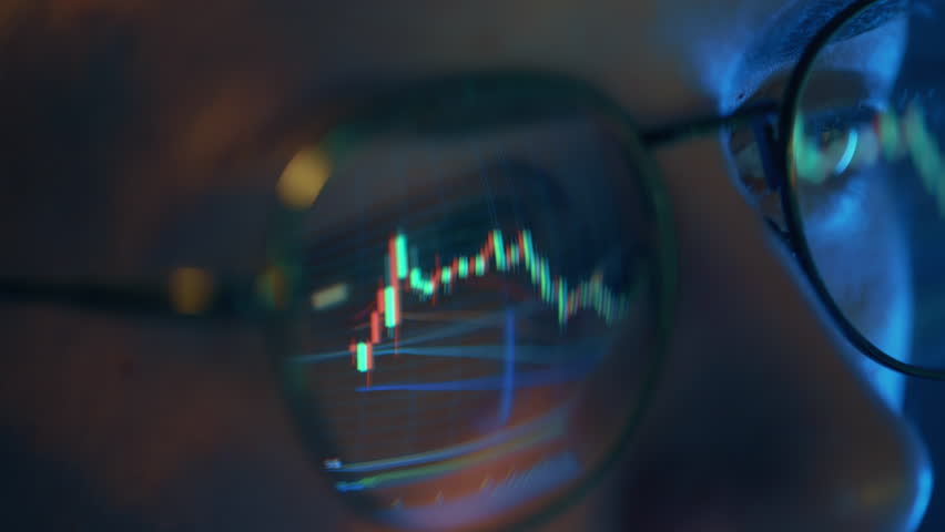 Trader wearing glasses is working on laptop computer. Screen with stock market charts and Bitcoin BTC or Ethereum ETH data analysis reflection. Broker trading online. Altcoins crypto currency trading - Powered by Shutterstock - Get 15% off with code: PIKWIZARD15
