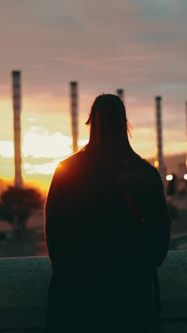 Vertical. Silhouette of a woman looking over Barcelona city skyline at night time