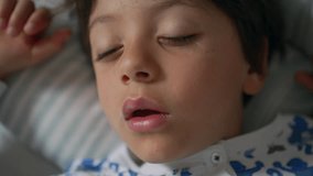 Close-up of a young boy sleeping with mouth slightly open, wearing printed pajamas, highlighting peaceful slumber on a pillow - Powered by Shutterstock - Get 15% off with code: PIKWIZARD15