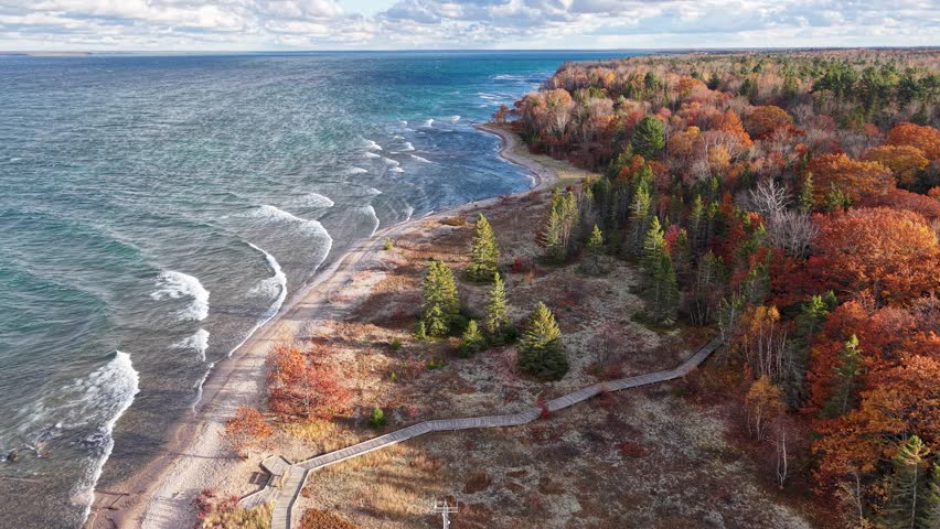 Drone footage of a rugged Lake Superior shoreline curving through vibrant fall foliage in Michigan’s Upper Peninsula