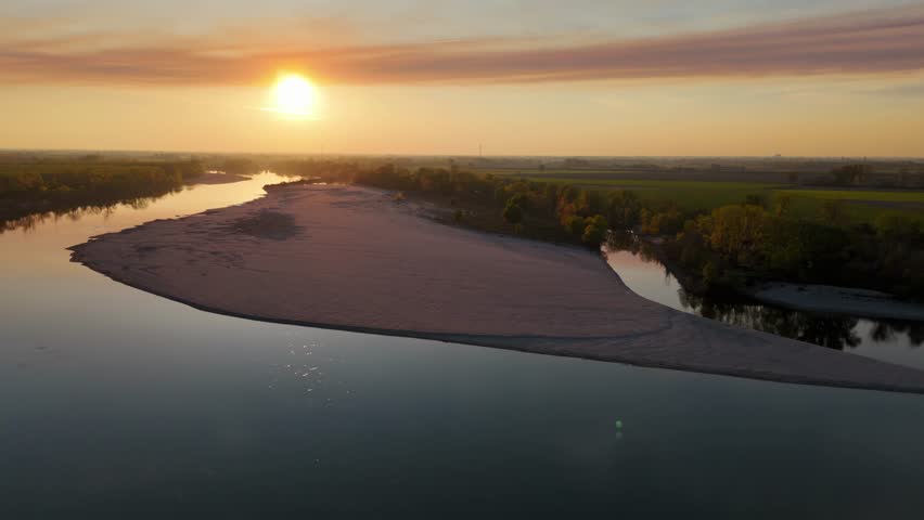 Golden sunset glimmers on the Adda River as pans over sandbar of Isola Serafini at the Adda Po confluence, forested Lombardy banks frame mirrored water under cirrostratus fibratus clouds, slow motion