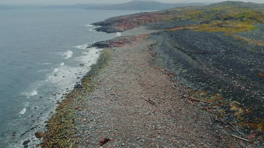 Aerial coastal exploration: rocky shoreline and expansive ocean view in motion