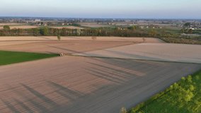 At golden-hour a lone tractor glides across rippled soil bands near Olza di Castelvetro Piacentino casting elongated shadows that cross plowed and pre-seeded furrows under warm light in slow motion - Powered by Shutterstock - Get 15% off with code: PIKWIZARD15