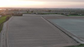 Sunset light glows across alternating plowed and pre-seeded furrows under soft haze as the drone hovers over expansive fields near Olza di Castelvetro Piacentino, Italy, slow motion - Powered by Shutterstock - Get 15% off with code: PIKWIZARD15