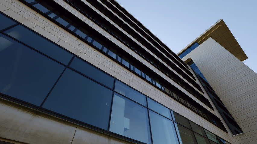 Modern office building with panoramic windows on facade in downtown low angle shot. Minimalist urban architect project for business and commerce on city street. Landmark view
