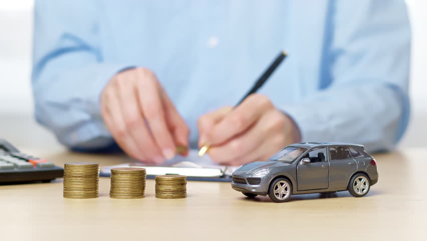 Concept of buying a car on credit, insurance. Hand stacking coins as accumulation of money.