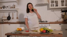 Close-up of a pregnant woman eating fresh celery in the kitchen, she is preparing a salad of fresh vegetables. - Powered by Shutterstock - Get 15% off with code: PIKWIZARD15