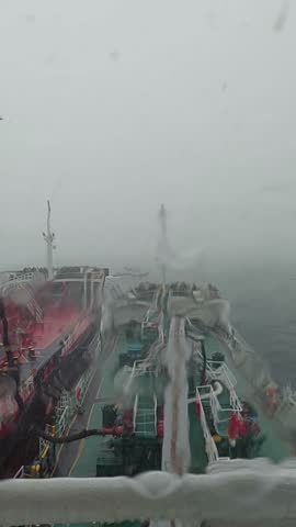 Two oil tankers performing a ship-to-ship (STS) transfer operation during a rainstorm. Taken from the bridge of one vessel, the scene captures the intensity of maritime operations in rough weather.