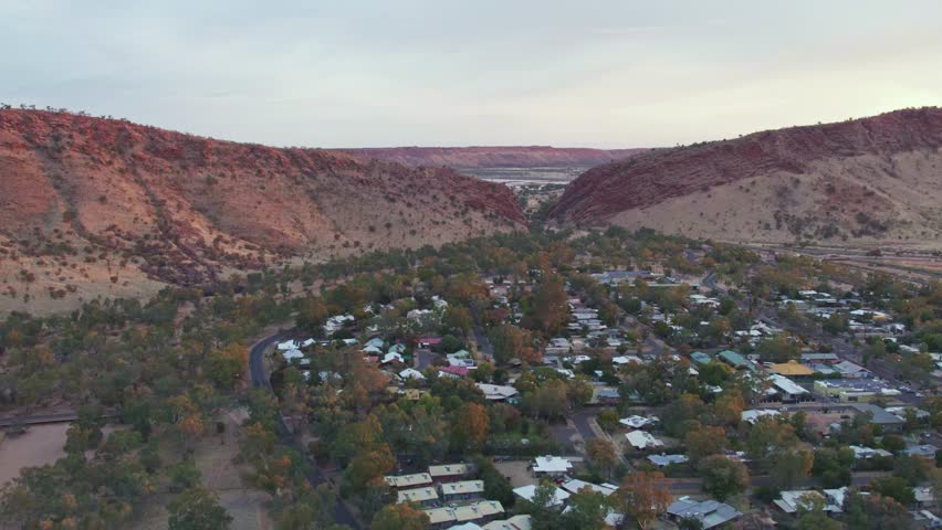 Aerial view moving towards Heavitree Gap at sunset, Alice Springs. Northern Territory, Australia. August 2022.