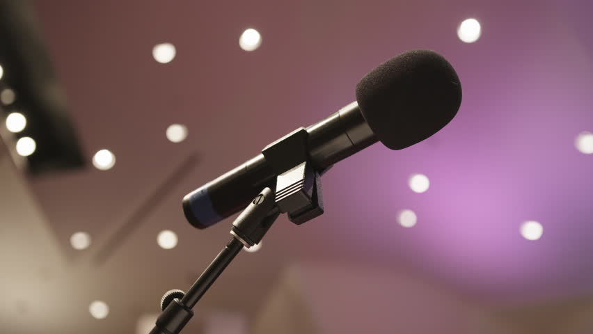 Wide shot of a peaceful, non-denominational church sanctuary or school auditorium with a microphone on a stand—capturing the quiet ambiance of a neutral, multipurpose space ready for gathering.