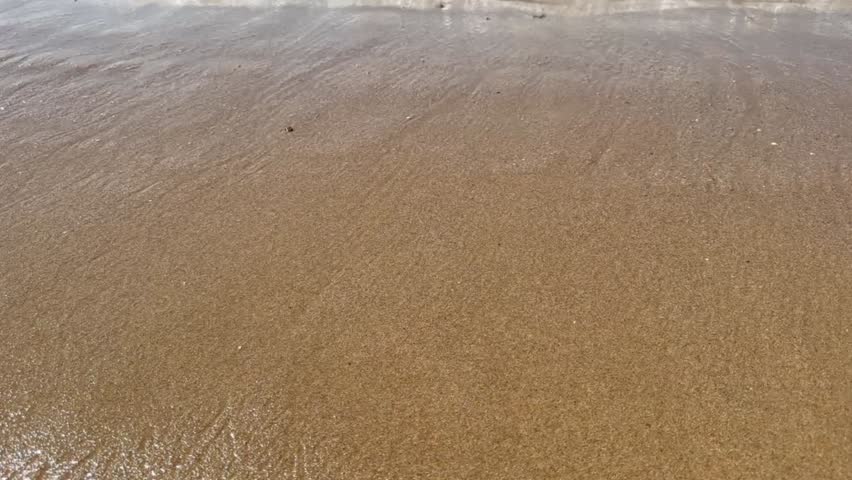 Close up of the sea lapping the shore on a sandy beach
