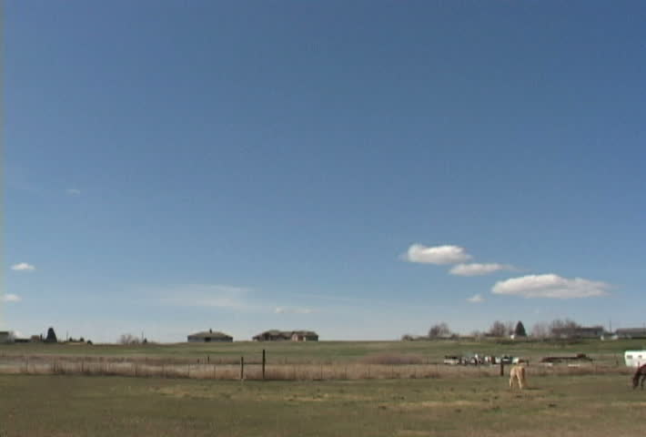 Time Lapse of farm house and horses grazing in pasture.