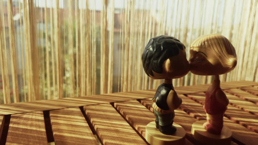 Romantic Kissing Couple Toys on Wooden Table in Warm Sunlight