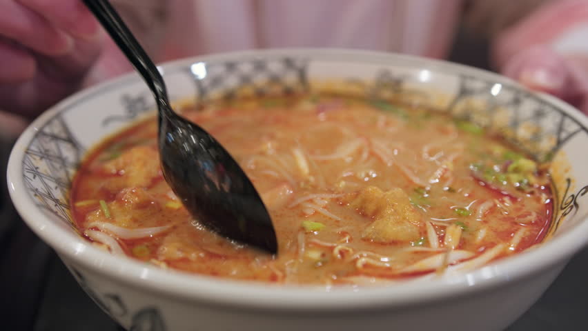 Woman eats Bun tom soup with shrimps, showing ingredients in close-up. Vietnamese dish.