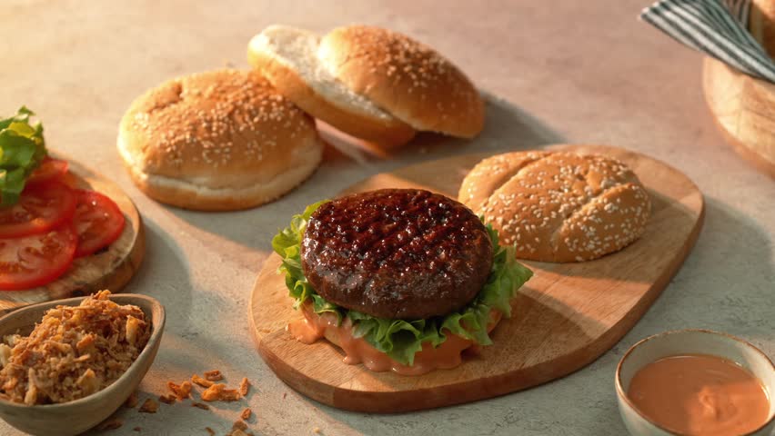 4K slow motion video of a cheese slice landing perfectly on a sizzling burger patty with lettuce, sauce and bun. A juicy, appetising food shot ideal for cooking, fast food, and grilling content.