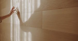 Woman's hand strokes a wooden wall, her shadow projected by natural window light. Slow motion captures the gentle, artistic movement, creating a tranquil and aesthetic feel. - Powered by Shutterstock - Get 15% off with code: PIKWIZARD15