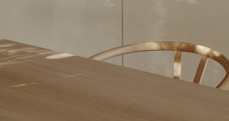 Sunlight streams through a window, casting playful shadows on a modern wooden table and the curved back of a matching chair. interior design, furniture, or lifestyle projects.