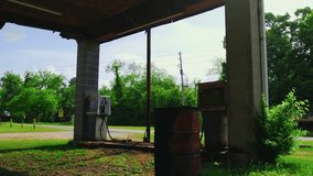 Low-angle view of a forgotten rural gas station in Georgia with rusted barrels, decayed pumps, and nature overtaking the lot. - Powered by Shutterstock - Get 15% off with code: PIKWIZARD15